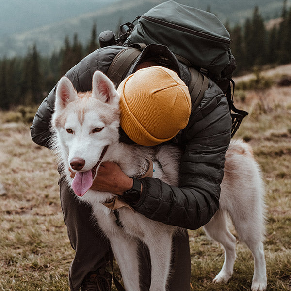 A person snuggling their dog out in the wilderness. 