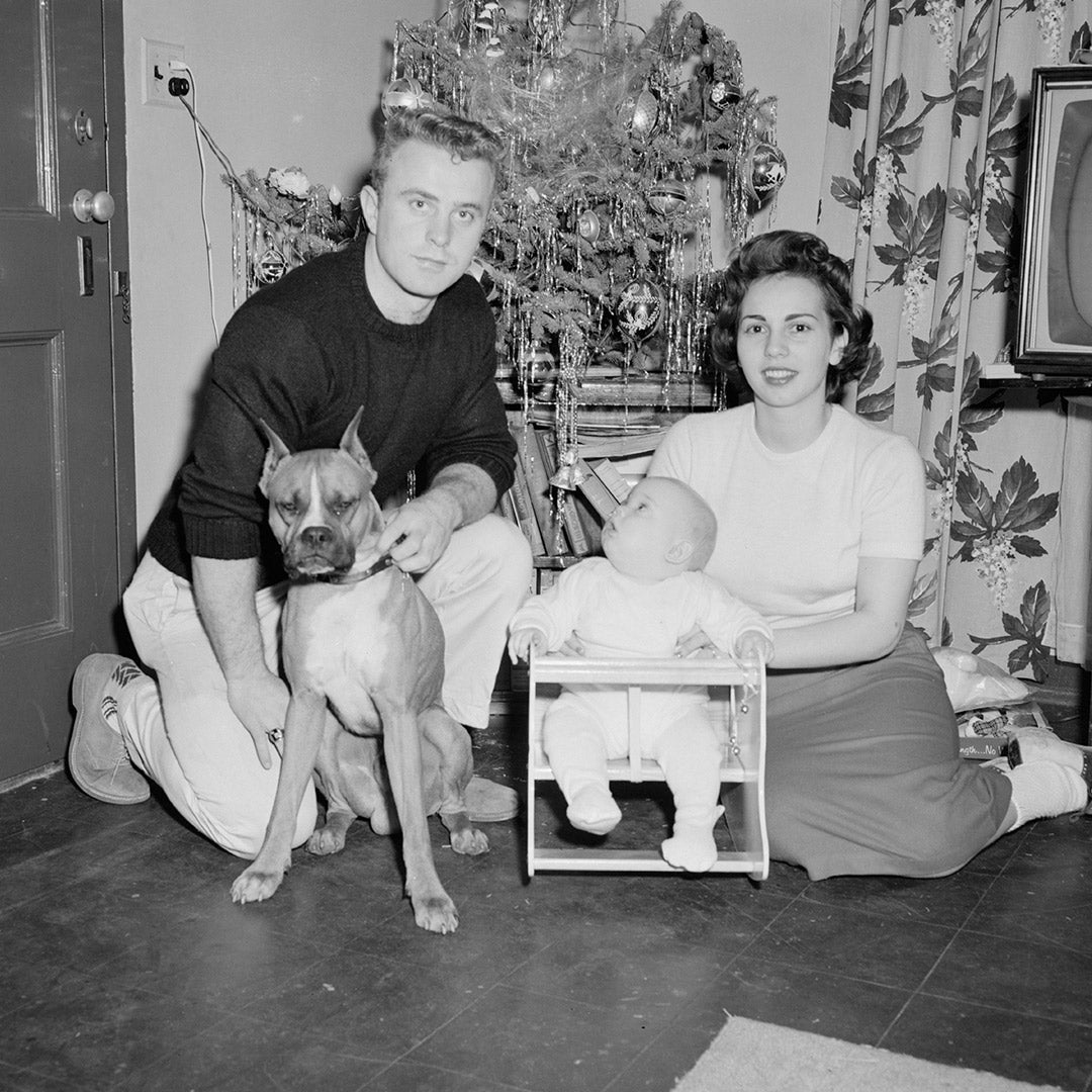 An old black and white photo of a family sitting with their dog, in front of a Christmas tree, at FurHaven Pet Products 